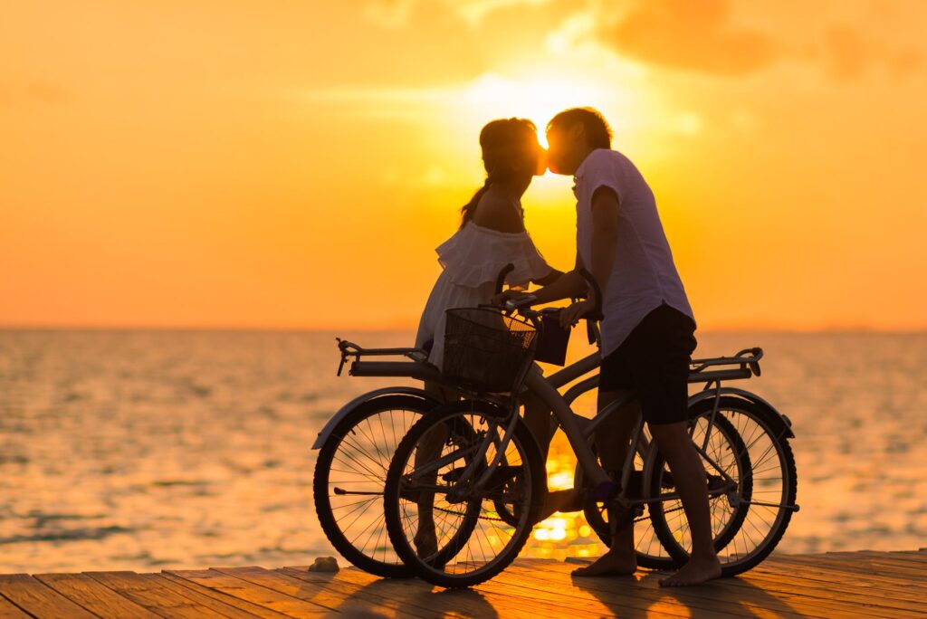 casal de bicicleta se beijando no pôr do sol, o foco da Psicologia Positiva é promover as qualidades do viver